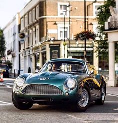 an old fashioned sports car driving down the street