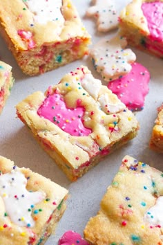 colorful cookies and sprinkles are arranged on a baking sheet with white frosting