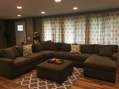 a living room filled with lots of furniture in front of a window covered in curtains