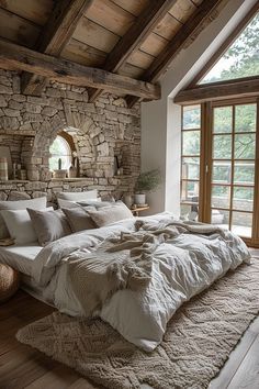 a large bed sitting under a window next to a stone wall in a living room