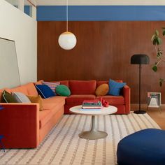 a living room with orange couches and blue accents on the walls, rugs and lamps