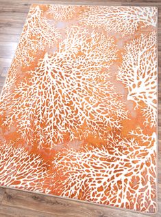 an orange and white area rug on the floor in a room with hardwood floors,