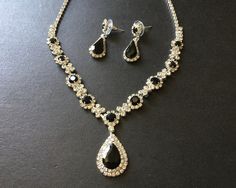 ** This listing comes with a necklace and a pair of matching earrings (studs at back design). ** Elegant shaped necklace set embellished with clear rhinestones crystals and black glass stones on top and linked to cable chain. We have also added an extra long cable chain at end for you to adjust the length. Size: necklace measures around 12.5" long x 1.45" center drop.  Earrings around 1.1" drop x 0.4" width  Color: silver with clear rhinestone crystals and black glass stones Item ship out with tracking number to you (around 10 to 14 business days for delivery). We also provide fast shipping service, around 3-4 business days delivery but need to add extra charge. Please convo us if need. Black Jewelry Set, Black Crystal Necklace, Wedding Art Deco, Black Stone Necklace, Dangle Necklace, Dangle Necklaces, Art Deco Necklace, Earrings Studs, Wedding Art