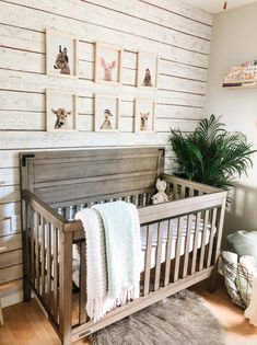 a baby's crib in the corner of a room with pictures on the wall