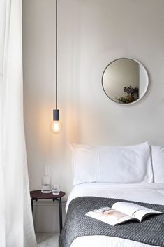 a bedroom with a bed, mirror and lamp on the wall next to a window