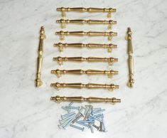 brass screws and nails are laid out on a marble surface