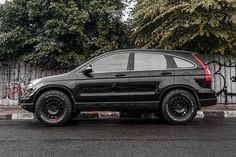 a black suv parked in front of a graffiti covered wall