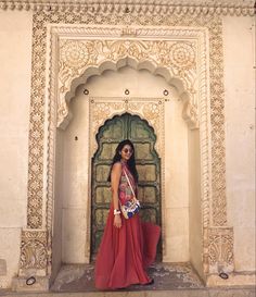 a woman is standing in front of an ornate doorway with her hand on her hip