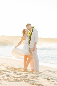 a bride and groom kissing on the beach