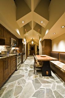 a kitchen with stone flooring and wooden cabinets, along with a dining table in the center