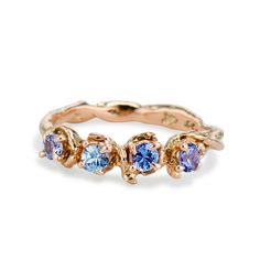 a gold ring with three blue stones on the side and two diamonds in the middle