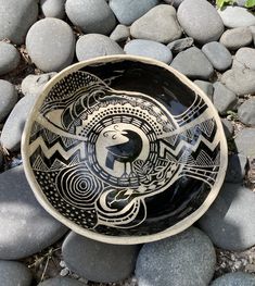 a black and white bowl sitting on top of rocks