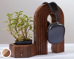 a potted plant in a wooden holder next to a pair of headphones on a stand