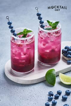 two glasses filled with blueberry lemonade and mint garnish on a tray