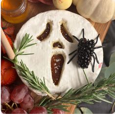 a cake decorated to look like a face with a spider on it, surrounded by fruit and vegetables