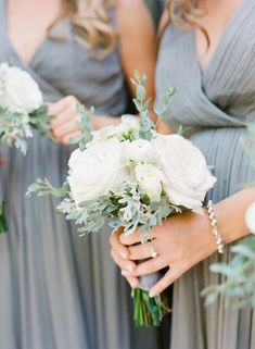 the bridesmaids are holding their bouquets with white flowers and greenery on them