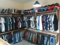 a room filled with lots of clothes and shoes on shelves next to a light hanging from the ceiling