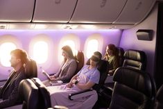 people sitting in seats on an airplane looking at their phones and laptops while they look out the windows