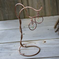 a pair of earrings is hanging from a metal stand on a wooden table next to some twigs