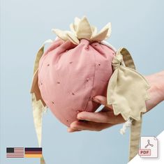 a hand holding a pink hat with bows on it