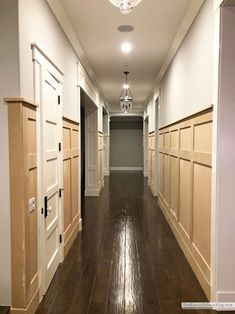 an empty hallway with white doors and wood floors