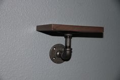 a close up of a light on a wall with a metal hook and wooden shelf