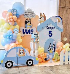 a blue car is parked in front of a backdrop with balloons and other decorations for a birthday party