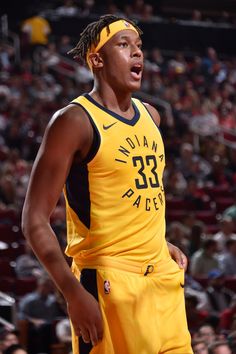 a basketball player wearing a yellow uniform in front of a crowd