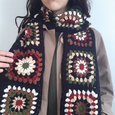 a woman wearing a black crocheted scarf with multicolored flowers on it