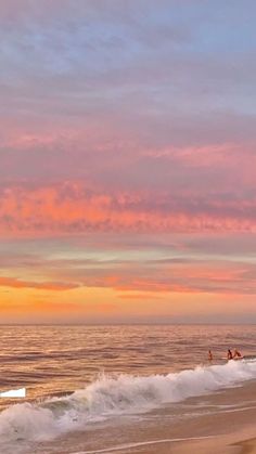 people on the beach at sunset with surfboards in the foreground and pink clouds in the background