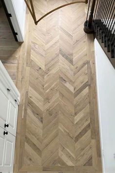 an overhead view of a wood floor in a kitchen with white cabinets and black stairs