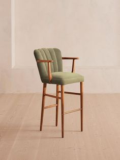 a wooden chair with a green upholstered seat and arm rest on a hard wood floor