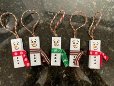 three snowmen made out of toilet paper with candy canes in their hands and tied to them