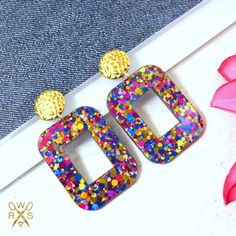 These statement earrings are the perfect addition to any wardrobe!  They feature hammered gold tone metal post tops and a rectangle crafted from a rainbow confetti acrylic. Cute, lightweight, and oh so swirly, these earrings are sure to add a bit of a party vibe to any outfit! ♥ Limited quantities available ♥ Stainless steel posts and rubber stopper backs make these hypoallergenic ♥ Take advantage of flat rate $3.95 shipping and FREE shipping with purchases $35+ Multicolor Rectangular Earrings For Party, Summer Resin Earrings, Pink Celebration, Laser Cut Earrings Acrylics, Party Vibe, Rainbow Confetti, Metal Post, Hand Painted Jewelry, Jewelry Accessories Ideas