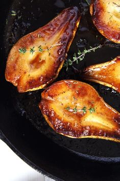 four pieces of chicken cooking in a skillet with some herbs on the top and side