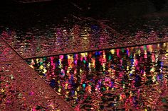 the reflection of lights on the wet pavement is shown in this photo, and it's very colorful