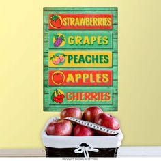 a basket full of apples next to a sign that reads strawberries grapes peaches apples cherries