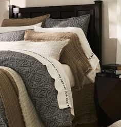 a bed with a black headboard and white comforter