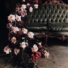 a green couch sitting next to a bunch of flowers