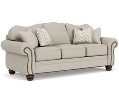 a beige couch with pillows on it and some brown trim around the armrests