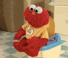 a red stuffed animal sitting on top of a toilet