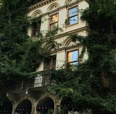 an old building with ivy growing on it's side and windows in the middle