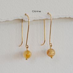 These elegant 14k gold drop earrings feature bright citrine gemstones. The long, hand-forged ear wires are gracefully curved and hammered, adding a touch of sophistication to the design.  Each earring showcases a smooth citrine bead that shimmers in the light, creating a beautiful pop of color. These earrings are perfect for both everyday wear and special occasions, offering a timeless and refined look. ✶ P R O D U C T ✶ D E T A I L S ✶ + 14k Gold Earwire in Gold Filled or Solid Gold + 8 mm Citrine Beads + Earring Drop Length is 2.75 inches ✶ P A C K A G I N G ✶ + Each piece is carefully packaged in an elegant microfiber pouch or a box and ready for gifting. + Orders with multiple pieces will be shipped in ONE BOX unless requested otherwise. + No invoice or pricing information will be prov Gold Citrine Gemstone Earrings, Handmade Gold Citrine Earrings, Elegant Faceted Citrine Earrings, Yellow Citrine Faceted Earrings, Yellow Faceted Citrine Earrings, Earrings Everyday, Citrine Beads, Citrine Gemstone, November Birthstone