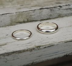 two wedding rings sitting on top of a wooden bench