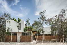 a white house surrounded by trees and sand