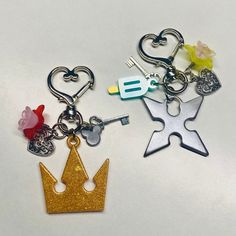 two key chains with charms attached to them, one has a heart and the other has a crown