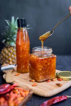 someone is spooning something out of a jar with food in it on a cutting board