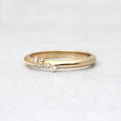 a gold ring with three small diamonds on the top and bottom, sitting on a white surface