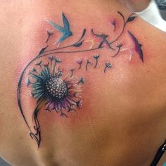 a woman with a tattoo on her back has a flower and birds flying around it