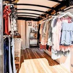 a room filled with lots of clothes hanging on the walls and wooden flooring in front of it